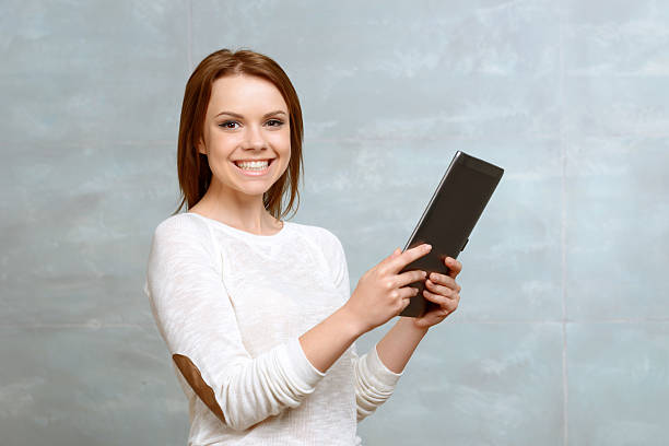 istock Smiling young woman standing with tablet 475796328