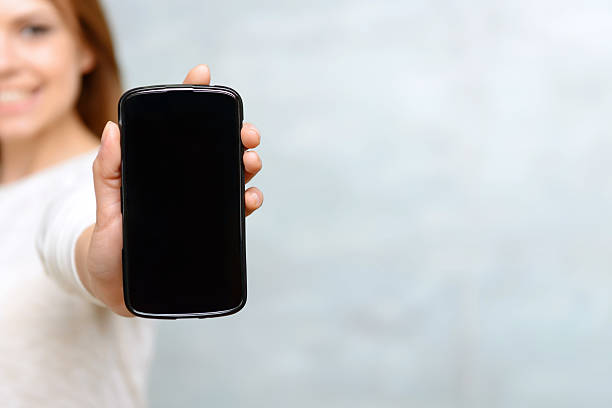 istock Smiling woman showing he mobile phone 475796338