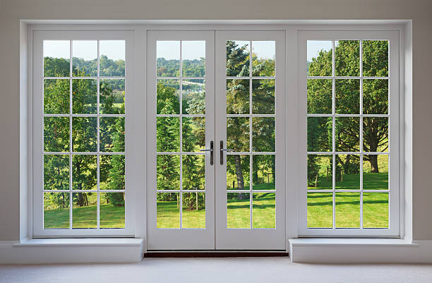 beautiful garden windows a set of finely crafted wooden Georgian style windows with doors set in a white frame, with white sills and caramel coloured walls. The view through the windows are towards a beautiful  countryside garden. window latch stock pictures, royalty-free photos & images