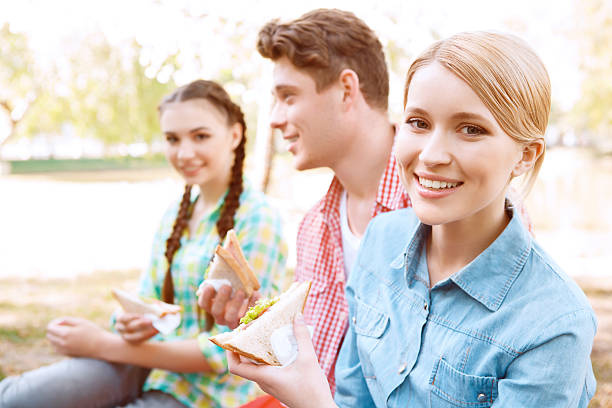 istock Young people sitting on cover and holding sandwiches 475806464