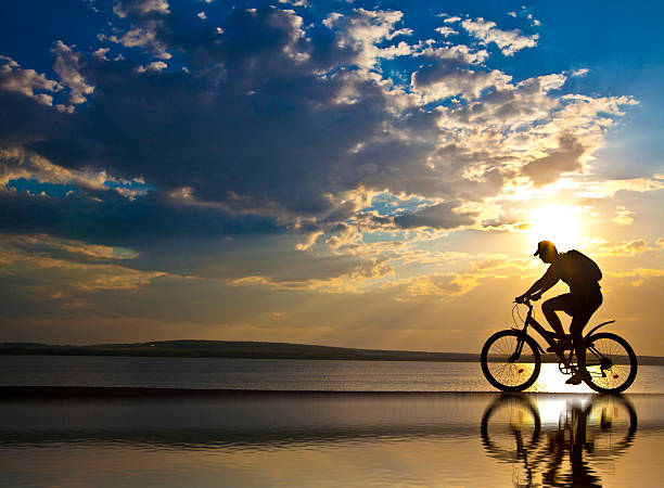 istock silhouette of a one cyclist at sunset with reflection 475812933