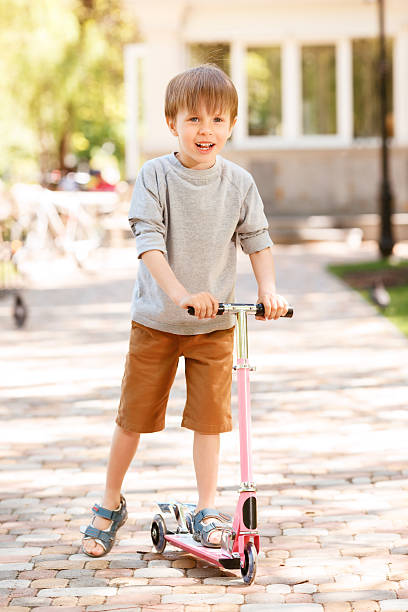 istock Smiling little boy riding scooter 475814922