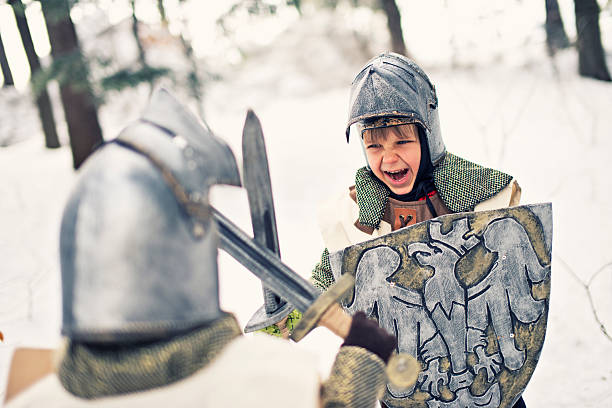 Little knights fighting in frozen forest Brave little knights fighting in frozen forest. On little boy is front to the camera, yelling. Second boy is back to the camera. Swords crossed. chain mail stock pictures, royalty-free photos & images