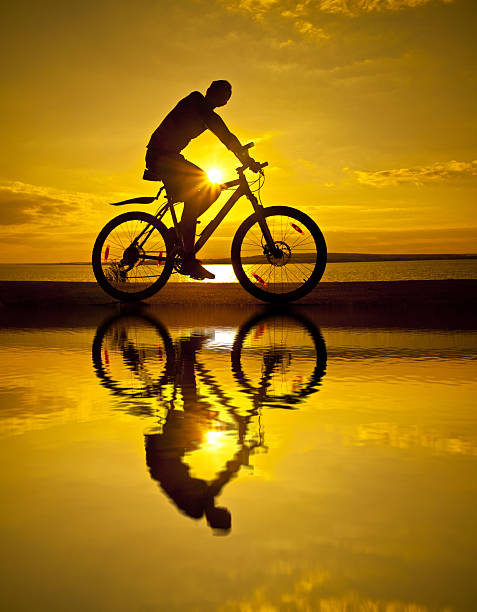 istock silhouette of  cyclist at sunset with reflection on water Copy 475825407