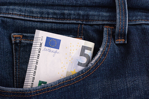 Five euro banknote in a pocket of blue jeans. Close up.