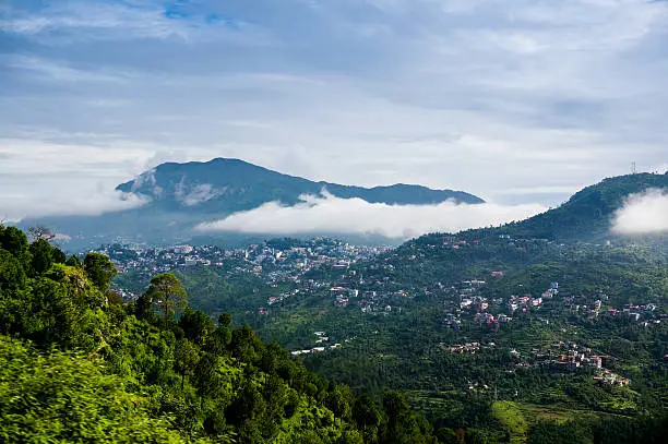 Clouds rolling between the hills of himachal pradesh in India. The small hill villages are visible among the green hills
