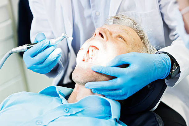 istock Light shining into male patient's mouth as dentist examines teeth 475839070