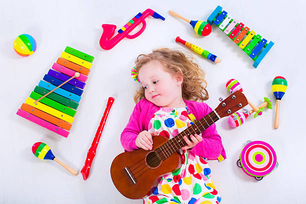 Child with music instruments. Musical education for kids. Colorful wooden art toys for kids. Little girl playing music. Kid with xylophone, guitar, flute.
