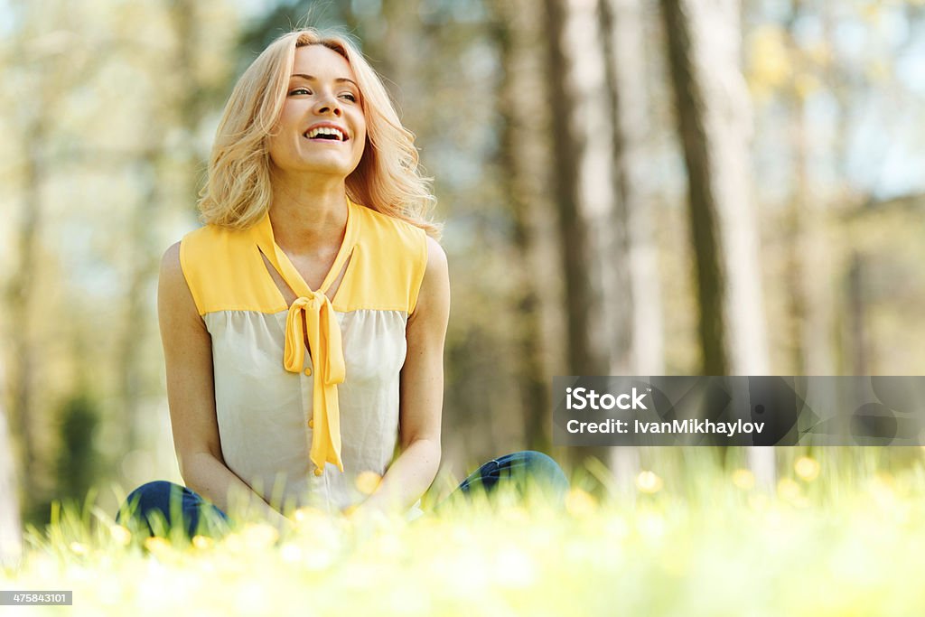 Woman sitting on grass Beautiful happy young woman sitting on grass Adult Stock Photo