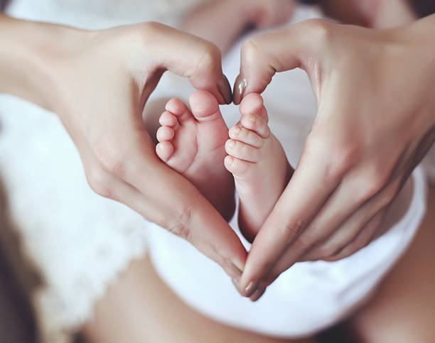 istock baby feets in mom hands holding them in heart shape 475843318