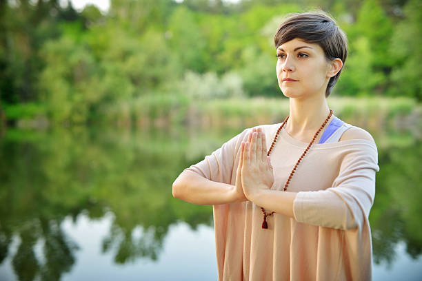 jovem mulher meditating - spirituality hand on heart meditating women - fotografias e filmes do acervo