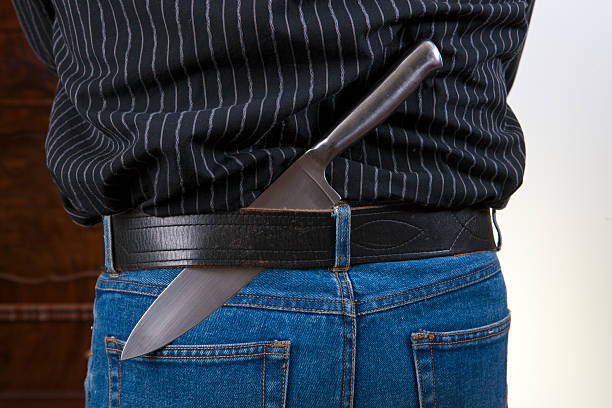 istock Young men in jeans Holding Knife Behind Back 475854113