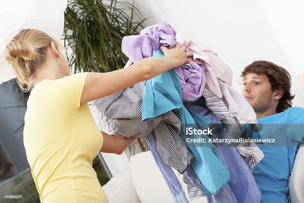 Lazy husband Lazy husband sitting on the couch while woman cleaning his clothes Adult Stock Photo