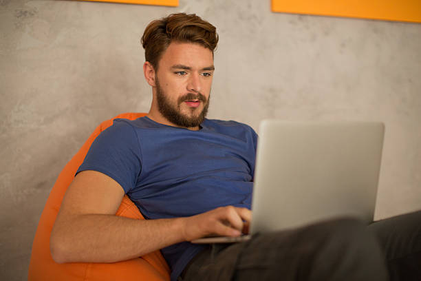 istock Man sitting in bean bag and using laptop. 475859650