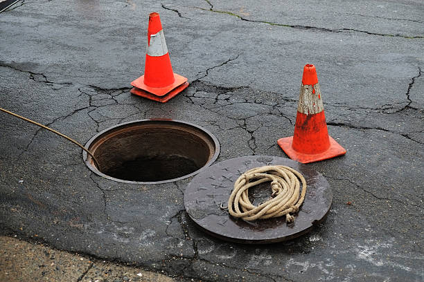 Open manhole with two orange cones. Open manhole for repair. manhole stock pictures, royalty-free photos & images