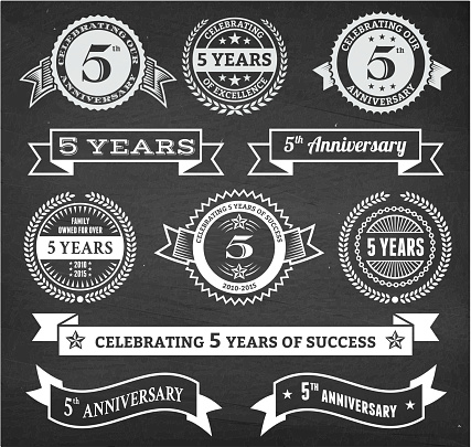 five year anniversary hand-drawn chalkboard royalty free vector background. This image depicts a black chalkboard with multiple anniversary announcement designs. There is chalk dust remaining on the chalkboard and the chalkboard texture serves a perfect backdrop for making the anniversary announcements look authentic and elegant.