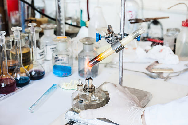 Chemical experiment - heating test tube: laboratory technician heating chemicals in test tube using laboratory lamp performing chemical experiment