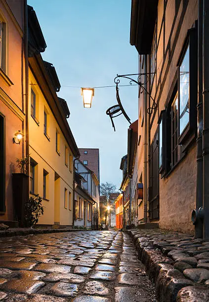 Wet street of historical Stralsund in Northern Germany. Focus on wet shiny cobblestones.
