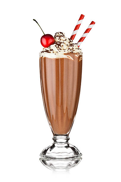 Chocolate milkshake with floating whipped cream Glass of chocolate milkshake with floating whipped cream topping chocolate sprinkles and cherry. Two red and white drinking straws emerges from the right of the shake. The glass is standing on reflective white background. DSRL studio photo taken with Canon EOS 5D Mk II and Canon EF 70-200mm f/2.8L IS II USM Telephoto Zoom Lens chocolate shake stock pictures, royalty-free photos & images