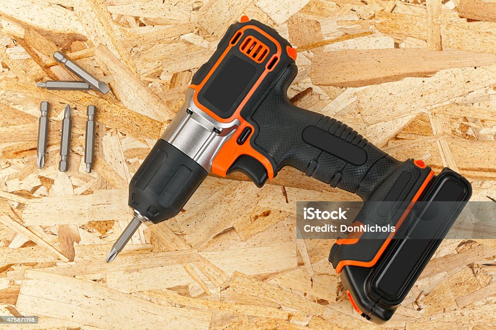 Cordless Drill Screw Driver Cordless drill with an assortment of various interchangeable screwdriver bits. Shot in studio on a wooden background with a DSLR camera. 2015 Stock Photo