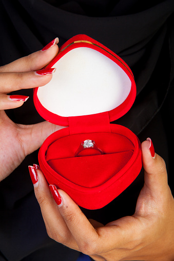 Female Muslim holding wedding ring in heart shape box