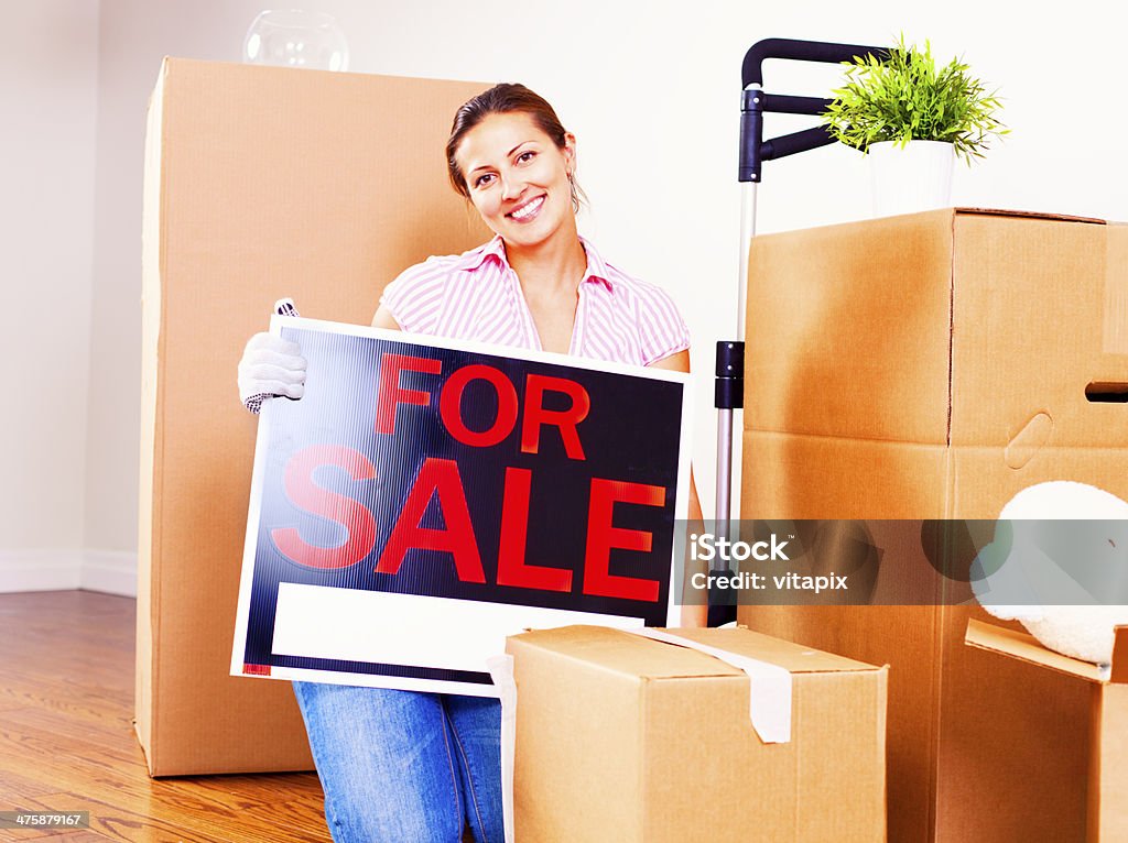 Selling Home Young woman sitting amongst cardboard boxes, preparing for a move. 20-29 Years Stock Photo