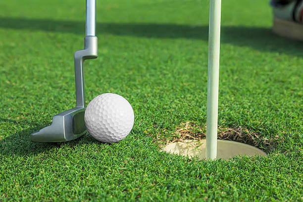istock putter puts a golf ball to hole on green 475896542