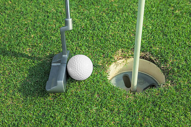 istock putter puts a golf ball to hole on green 475896548