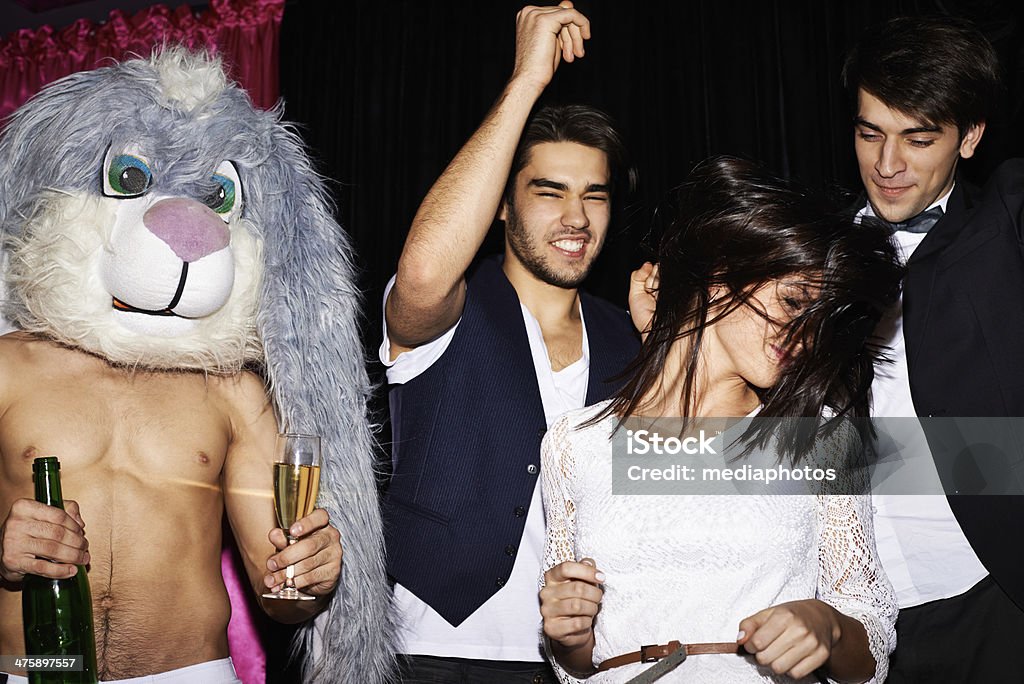 Energetic party-goers Energetic young people dancing in nightclub, one of them wearing rabbit head Dance Floor Stock Photo