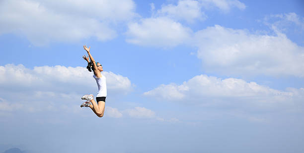 istock freedom young asian woman jumping against blue sky 475903708