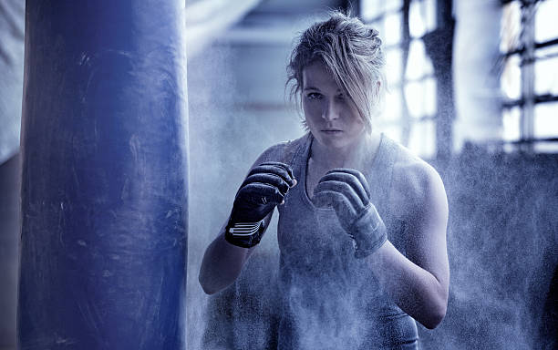 Female boxer in an abandoned warehouse Female boxer in an abandoned warehouse. women boxing sport exercising stock pictures, royalty-free photos & images