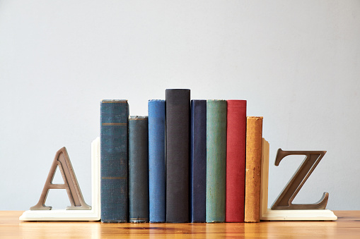 A small collection of traditionally bound books, sitting between two bookends.