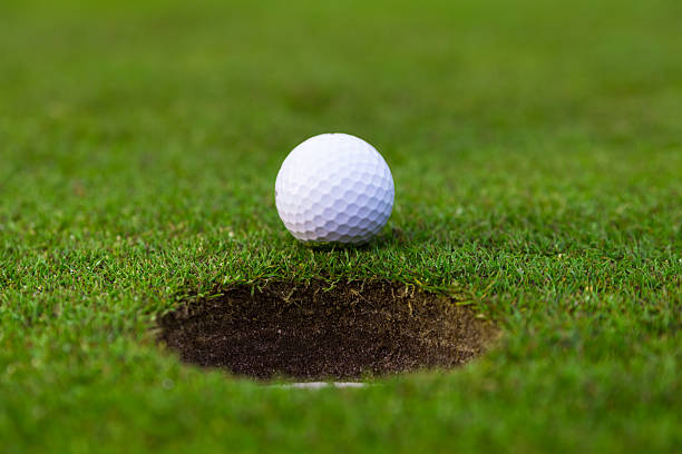 istock golf ball on lip of cup. 475914057