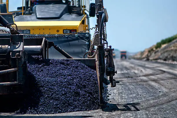 Photo of Industrial pavement machine laying fresh asphalt on highway