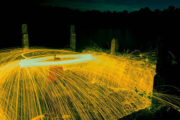 Firework showers of hot glowing sparks from spinning steel wool on the beach.