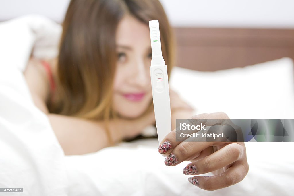 Woman Checking Pregnancy Test on bed Close up Woman Checking Pregnancy Test on bed Examining Stock Photo