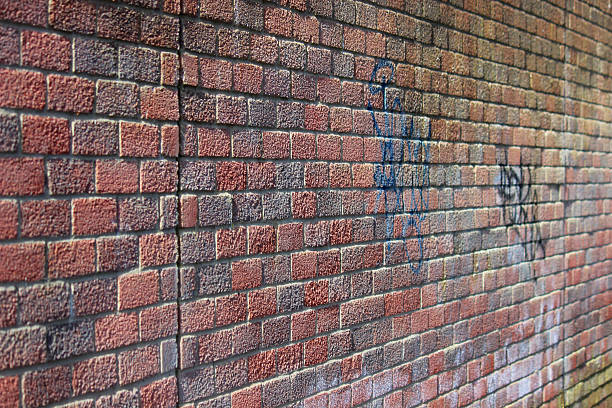istock Image of sunny red brick wall, with graffiti and textured-surface 475920534