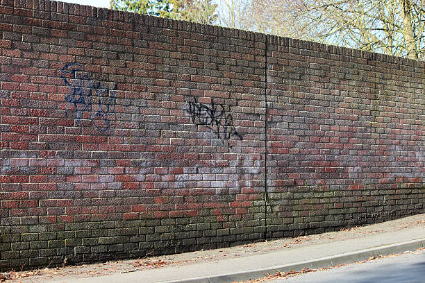 istock Image of red brick wall next to road / pavement, graffiti 475920546