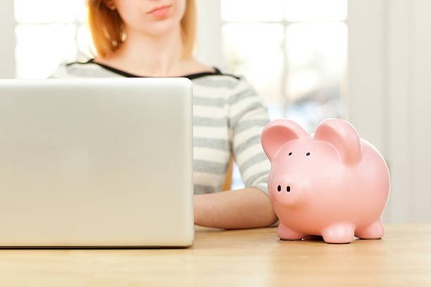 istock Woman with Piggy Bank Using Laptop Computer for Online Banking 475922607