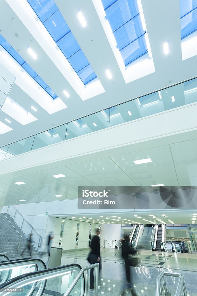 Gente cammina nel futuristico interno con finestre e scale mobili - Foto stock royalty-free di Centro commerciale