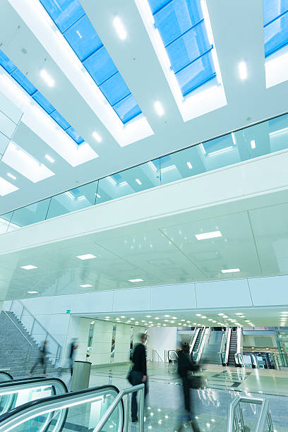 istock People Walking in Futuristic Interior With Escalators and Ceiling Windows 475923157