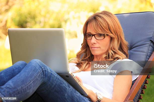 Mature Woman Working In The Garden On Her Laptop Stock Photo - Download Image Now - Laptop, Outdoors, Using Computer