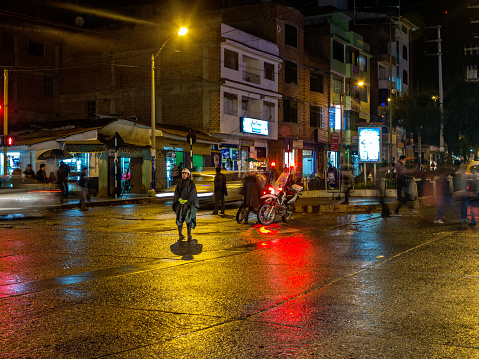 Huaraz, Peru - January 23, 2015: Police patrol at night on wet Peruvian city street. A policeman and pedestrians are pictured