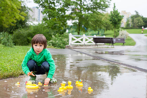 istock Little boy, jumping in muddy puddles in the park 475958576