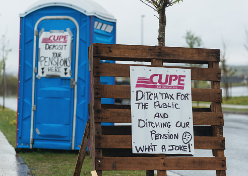 Halifax, Canada - May 31, 2015: Signs of protest line the sidewalk outside a Halifax Water Commission Headquarters during a CUPE unionized worker strike.  The key issue being disputed in the strike is a plan to reduce worker pensions. 