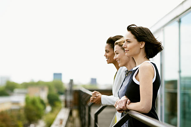 Coworkers getting fresh air smiling business women enjoying the view from the terrace businesswomen group stock pictures, royalty-free photos & images