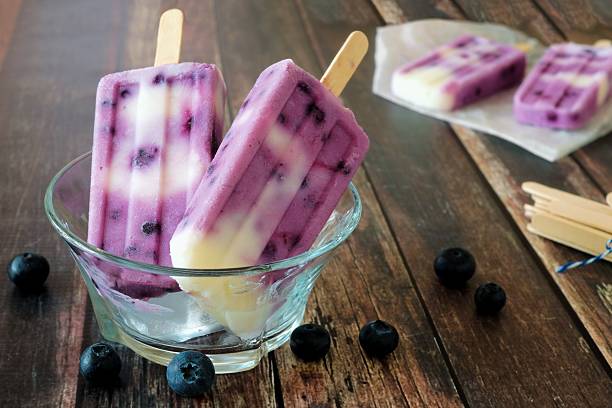 istock Blueberry vanilla popsicles in a clear bowl against wood 475970226