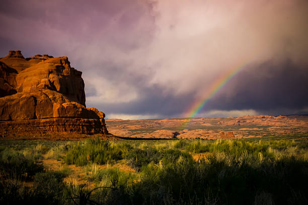 Beautiful Rainbow under Stormy Sky and Red Rocks. Taken at Arches National Park in Moab, Utah.