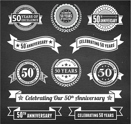 fifty year anniversary hand-drawn chalkboard royalty free vector background. This image depicts a black chalkboard with multiple anniversary announcement designs. There is chalk dust remaining on the chalkboard and the chalkboard texture serves a perfect backdrop for making the anniversary announcements look authentic and elegant.