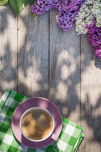 istock Coffee cup and colorful lilac flowers on garden table 475971922